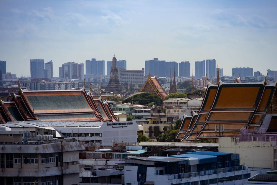 Vue panoramique de Bangkok avec des temples traditionnels et des immeubles modernes en arrière-plan.