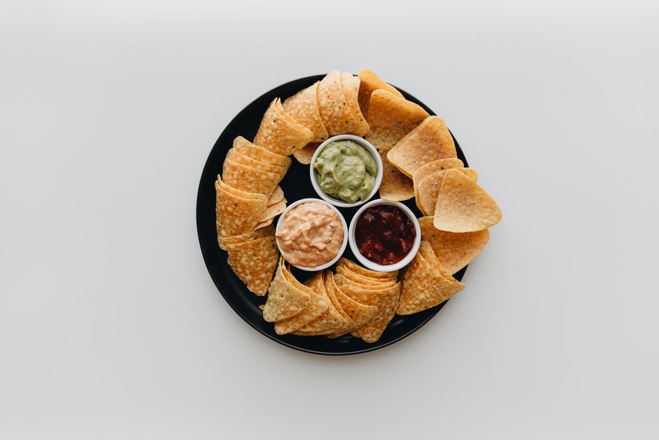 Assiette de chips de légumes au four avec sauces guacamole, salsa et crème. Chips de betterave et patate douce.