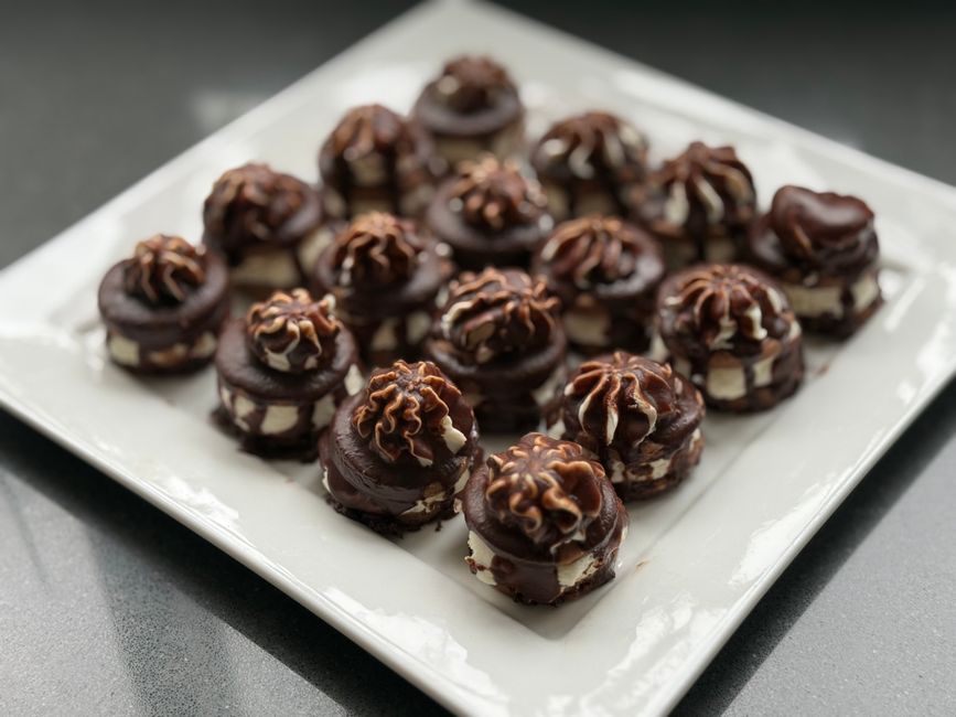 Assortiment de mini desserts chocolatés garnis de crème sur un plat carré, parfaits pour un apéritif gourmand.