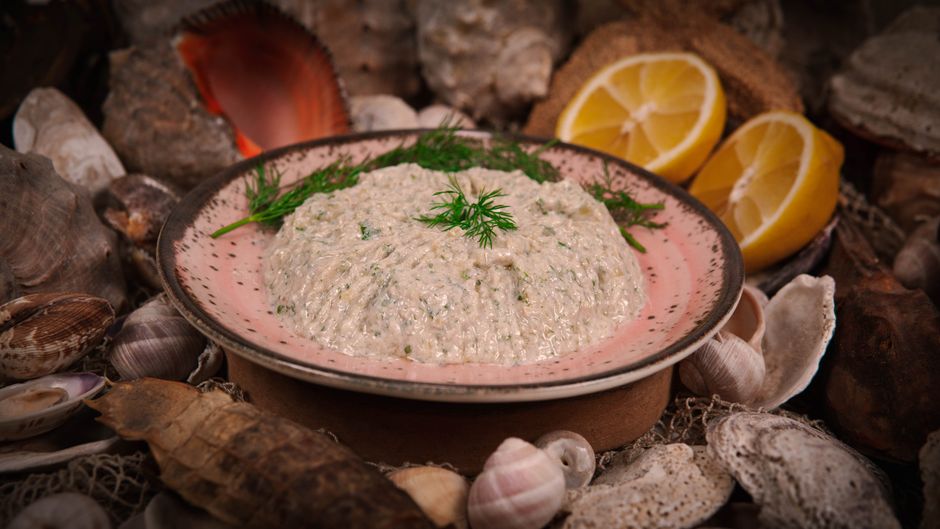Rillettes de thon au citron et aux herbes servies dans une assiette sur un fond de coquillages et de citrons.