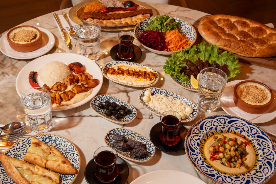 Table garnie de plats variés, incluant houmous, viandes, salades et pains, pour accompagner la recette de tartinade.