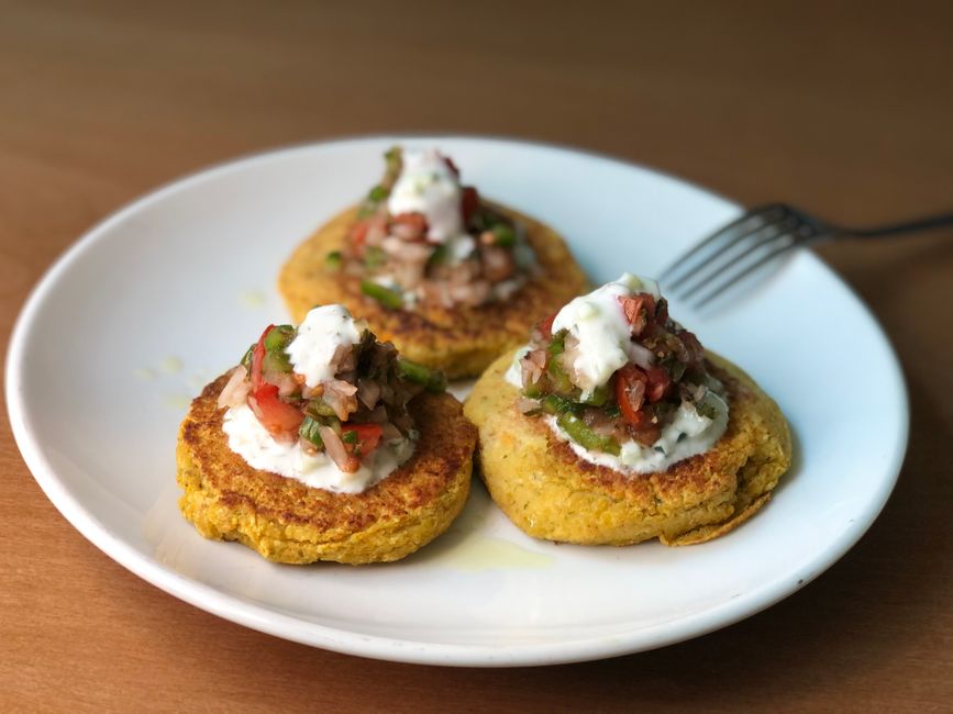 Bouchées de courgette et chèvre au four garnies de salsa et crème, servies sur une assiette blanche.