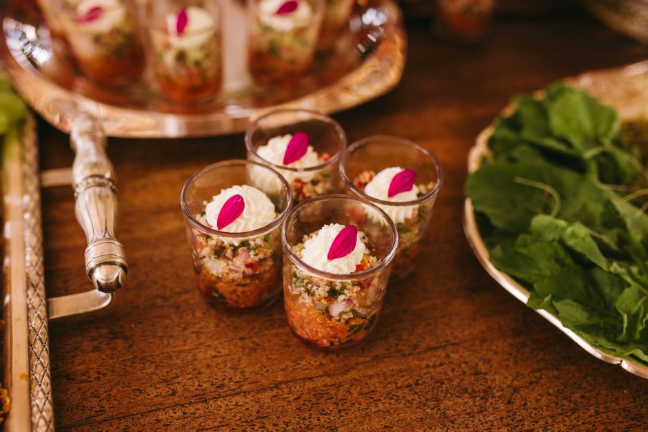 Verrines apéritives garnies de légumes, fromage et pétales de fleurs sur une table en bois.