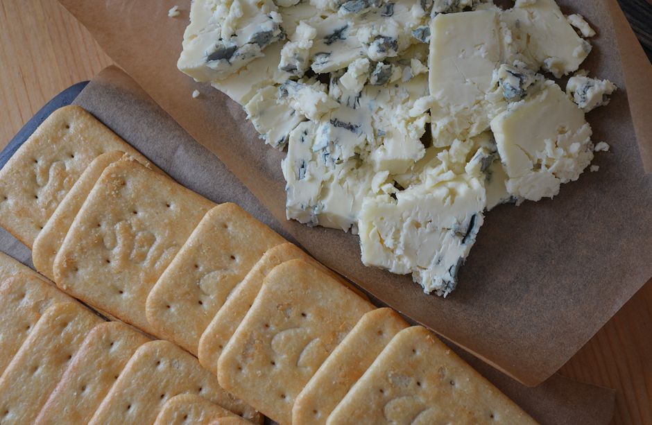 Crackers aux graines accompagnés de fromage bleu sur un plateau en bois. Parfait pour les tartinades.