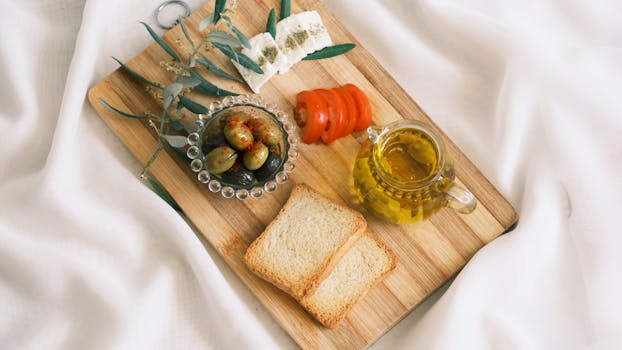 Plateau apéritif avec pains sans pétrissage, olives, tomates, huile d'olive et fromage sur une planche en bois.