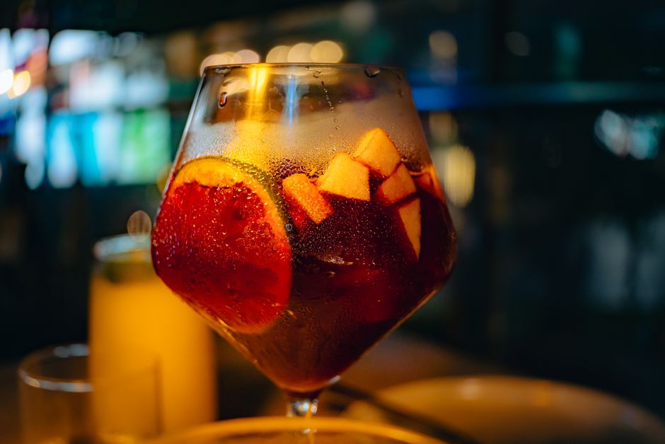 Verre de sangria blanche avec des tranches de citron et des morceaux de pomme, décoré, sur fond flou.