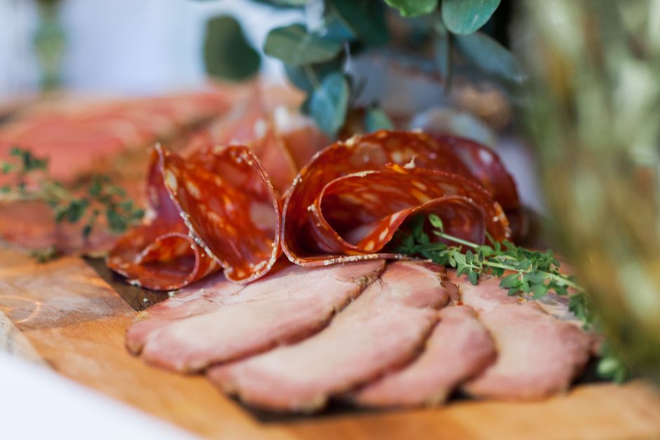 Planche apéro avec charcuterie variée, incluant des tranches de viande et des herbes fraîches.