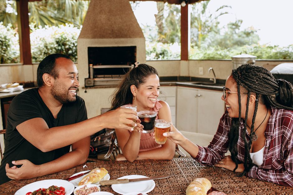 Groupe d'amis levant des verres lors d'un apéritif en extérieur, avec de la nourriture sur la table.