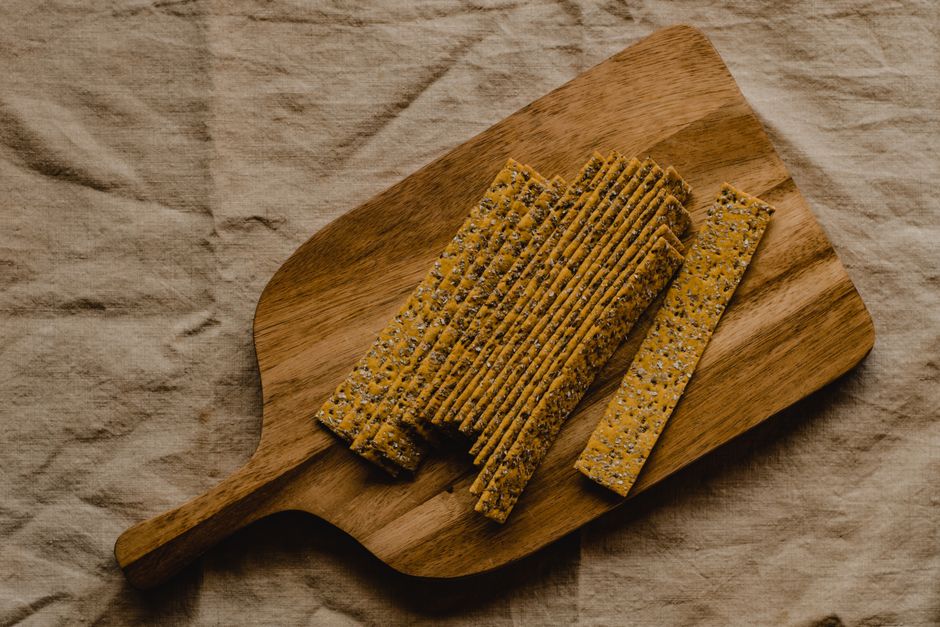 Crackers aux graines disposés sur une planche en bois, idéaux pour accompagner des tartinades.