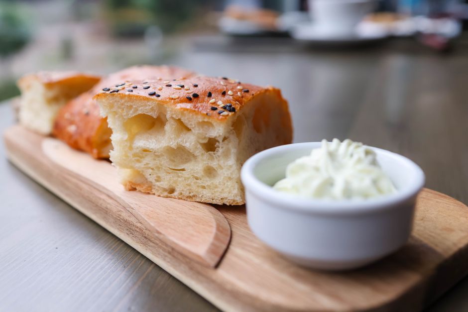 Focaccia dorée et moelleuse servie avec une petite coupelle de crème.