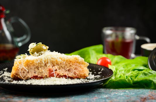 Une part de pain sans pétrissage garnie de tomates, fromage et olives, servie avec de la salade.