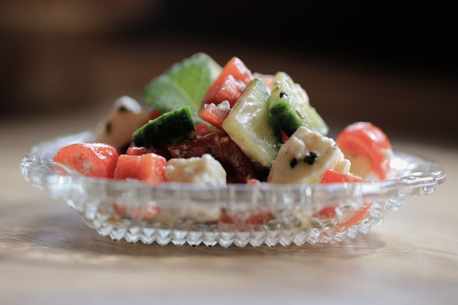 Salade colorée de tomates, concombre et feta dans un plat en verre, idéale pour accompagner une crème de feta fouettée.