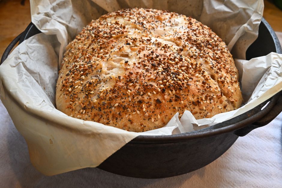 Pain sans pétrissage cuit dans une cocotte, recouvert de graines et avec une croûte dorée et croustillante.