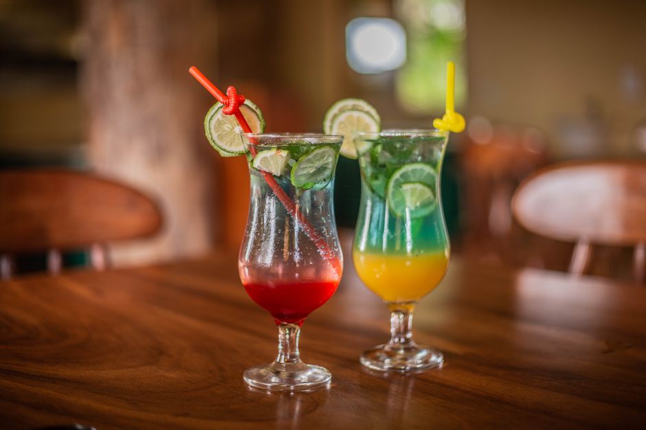Deux cocktails sans alcool colorés dans des verres décoratifs, garnis de rondelles de citron vert et de pailles.