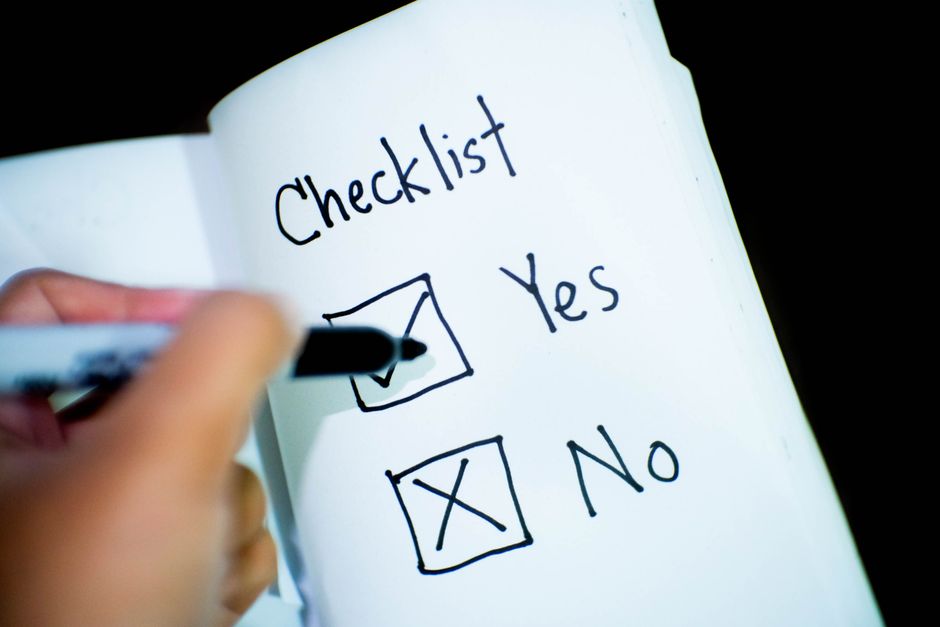 Main cochant une case "Yes" sur une checklist, symbolisant l'organisation d'un apéro dinatoire.