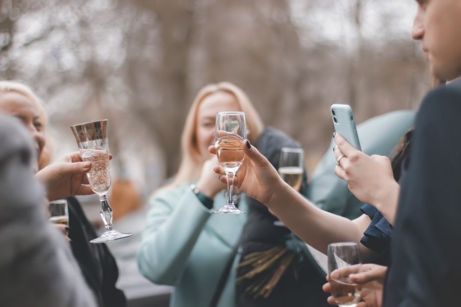 Groupe d'amis levant leurs verres lors d'un apéritif en extérieur, ambiance festive et conviviale.