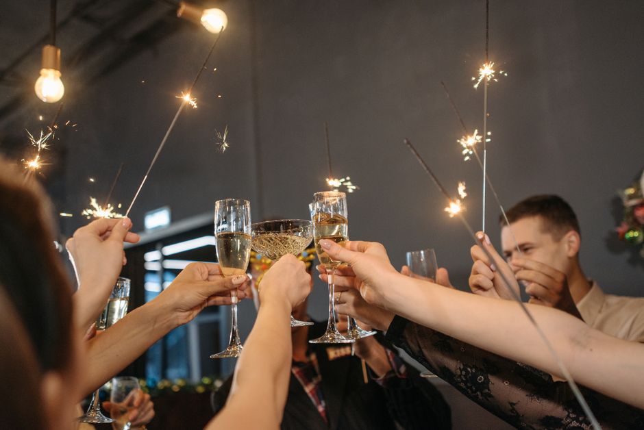 Groupe d'amis levant des coupes de champagne avec des pétards à étincelles lors d'un apéritif festif.