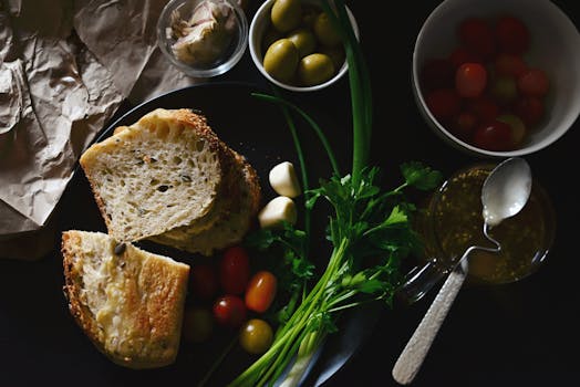 Pain sans pétrissage, tapenade, tomates cerises, olives et herbes fraîches sur une table pour un apéro maison.