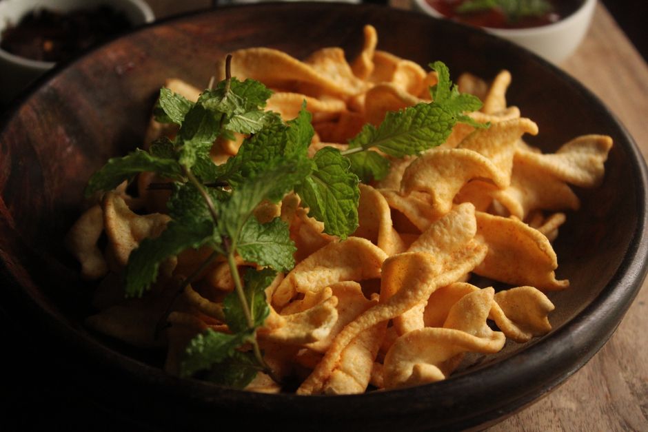 Bol en bois rempli de chips de légumes au four, garnies de feuilles de menthe fraîche.