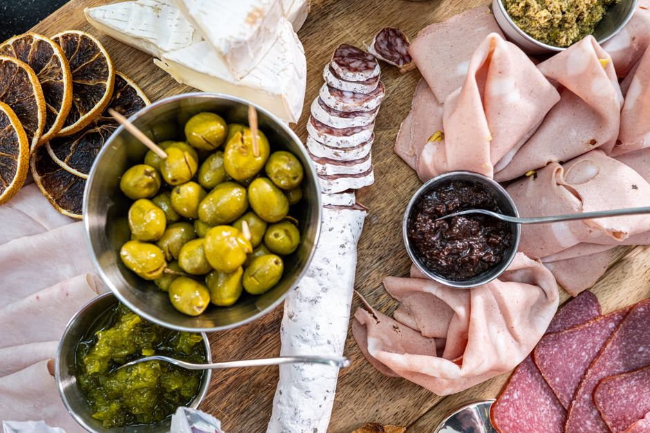 Planche apéro équilibrée avec charcuterie, fromages, olives, tapenade et fruits secs sur une planche en bois.